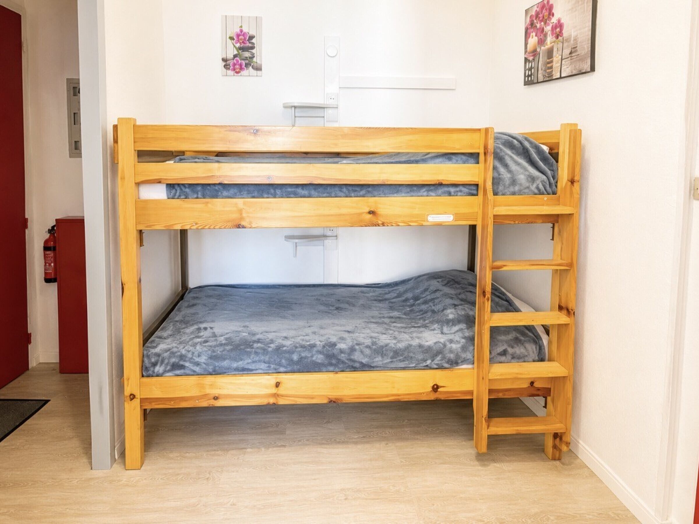 A bunk bed with a ladder, a fire extinguisher, and artwork on the walls.