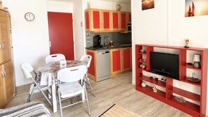 Un espace de vie compact comprenant un coin repas, une kitchenette et un meuble pour la télévision.