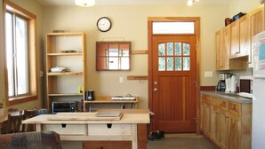 Una cucina compatta con mobili in legno, un forno a microonde, una macchina da caffè e un tavolo da pranzo con sedie.