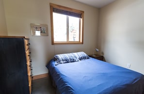 A bedroom with a bed, a window, a nightstand, and a dresser.