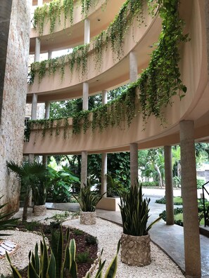 Een meerlaags atrium met kolommen, groen en plantenbakken.