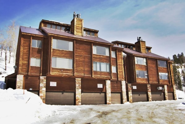 A two-story wooden building with multiple garage doors and a sloped roof.