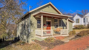 A small, single-story house with a porch, a chimney, and a brick pathway leading to the front door. - Cottage On Main- In The Heart Of Weston (Weston)