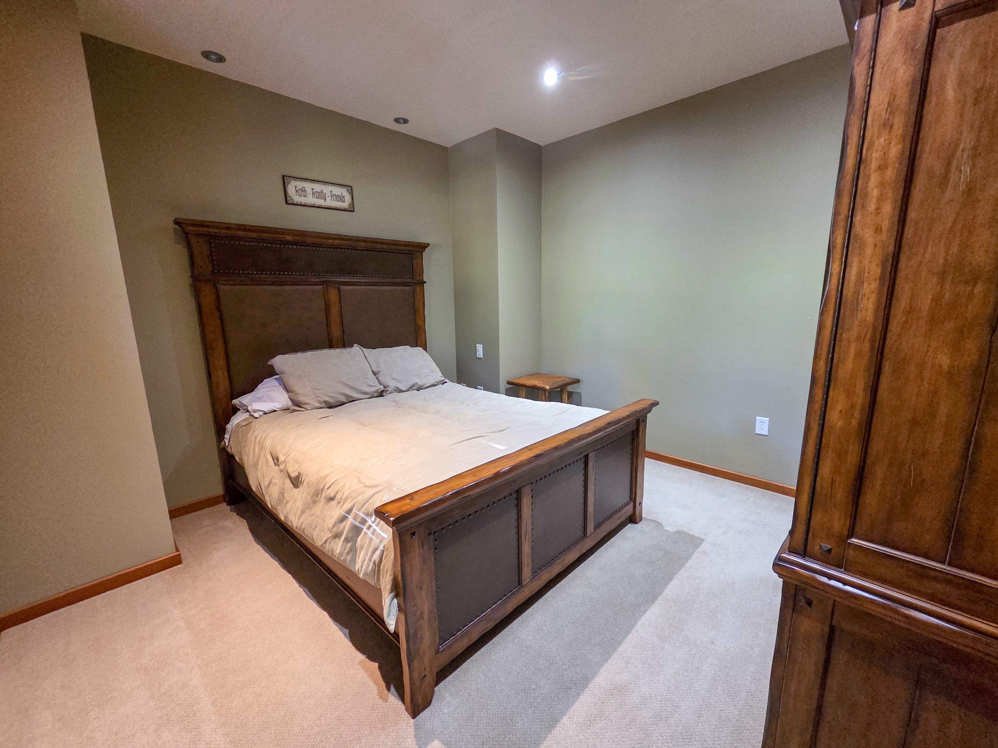 A bedroom with a wooden bed, a small bedside table, and a nightstand.
