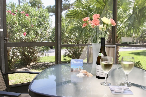 A table with a bottle of wine, two glasses, a card, and a small decorative item.