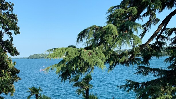 Un belvédère offrant une vue sur la mer, entouré de jardins bien entretenus et bordé d’un sentier en pierre.