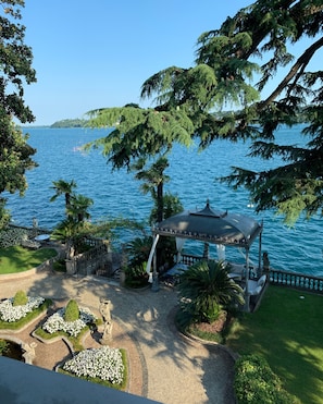 Un belvédère offrant une vue sur la mer, entouré de jardins bien entretenus et bordé d’un sentier en pierre.