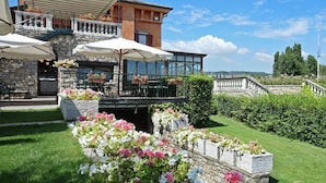 Un hôtel doté d’une terrasse, d’une façade en pierre et offrant une vue sur des drapeaux et des montagnes.