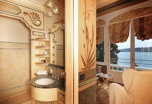 Une salle de bain avec un lavabo en marbre, un grand miroir et une vue sur la mer par la fenêtre.