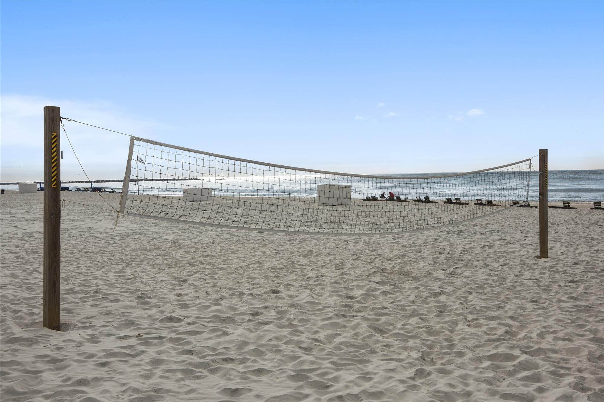 A beach volleyball net set up on a sandy beach with a clear sky.