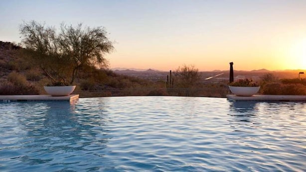 Una piscina con vistas a un paisaje desértico al atardecer.