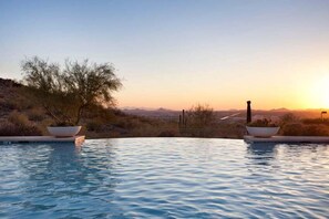 A pool with a view of a desert landscape during sunset.