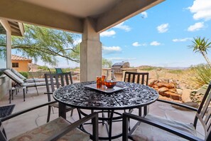 A patio with a round table, chairs, and a grill.