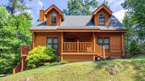 A log cabin with a porch, two chimneys, and a stone foundation. - Amazing Luxury Log Cabin! Great Living Space! Mountain Views! 2 Jacuzzi Tubs!  (Sevierville)