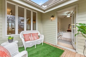 A covered patio with a white wicker sofa, a small table with a plant, and a green artificial turf. - Elegant Downtown Chattanooga Retreat Near Riverfront & UTC Sleeps 6 Fireplace (Chattanooga)