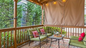 A wooden deck with a covered area, furnished with green chairs and a table, and string lights. - Elegant Downtown Chattanooga Retreat Near Riverfront & UTC  Sleeps 6 Fireplace (Chattanooga)