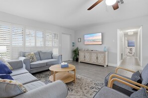 A modern living room with a grey sofa, a round coffee table, and a television on the wall.