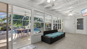 Une pièce spacieuse dotée de grandes portes-fenêtres coulissantes donnant accès à un espace piscine extérieur.
