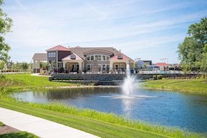 A large, multi-story building with a fountain in front, surrounded by a well-maintained lawn and a pond. - Minutes from Bethany Beach Boardwalk! (Millville)