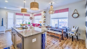 Una cocina moderna con una isla central, suelo de madera e iluminación colgante.
