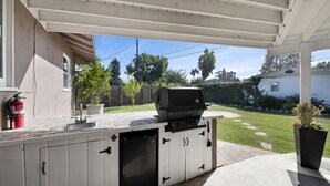 Ein Outdoor-Kochbereich mit integriertem Grill, einer Spüle und einem Feuerlöscher.