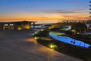 Un resort con piscina, vistas al atardecer y un sendero pavimentado.