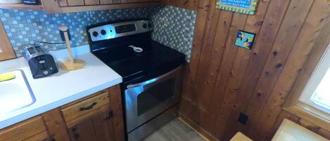 A kitchen with wooden cabinets, a microwave, an oven, and a tiled backsplash.