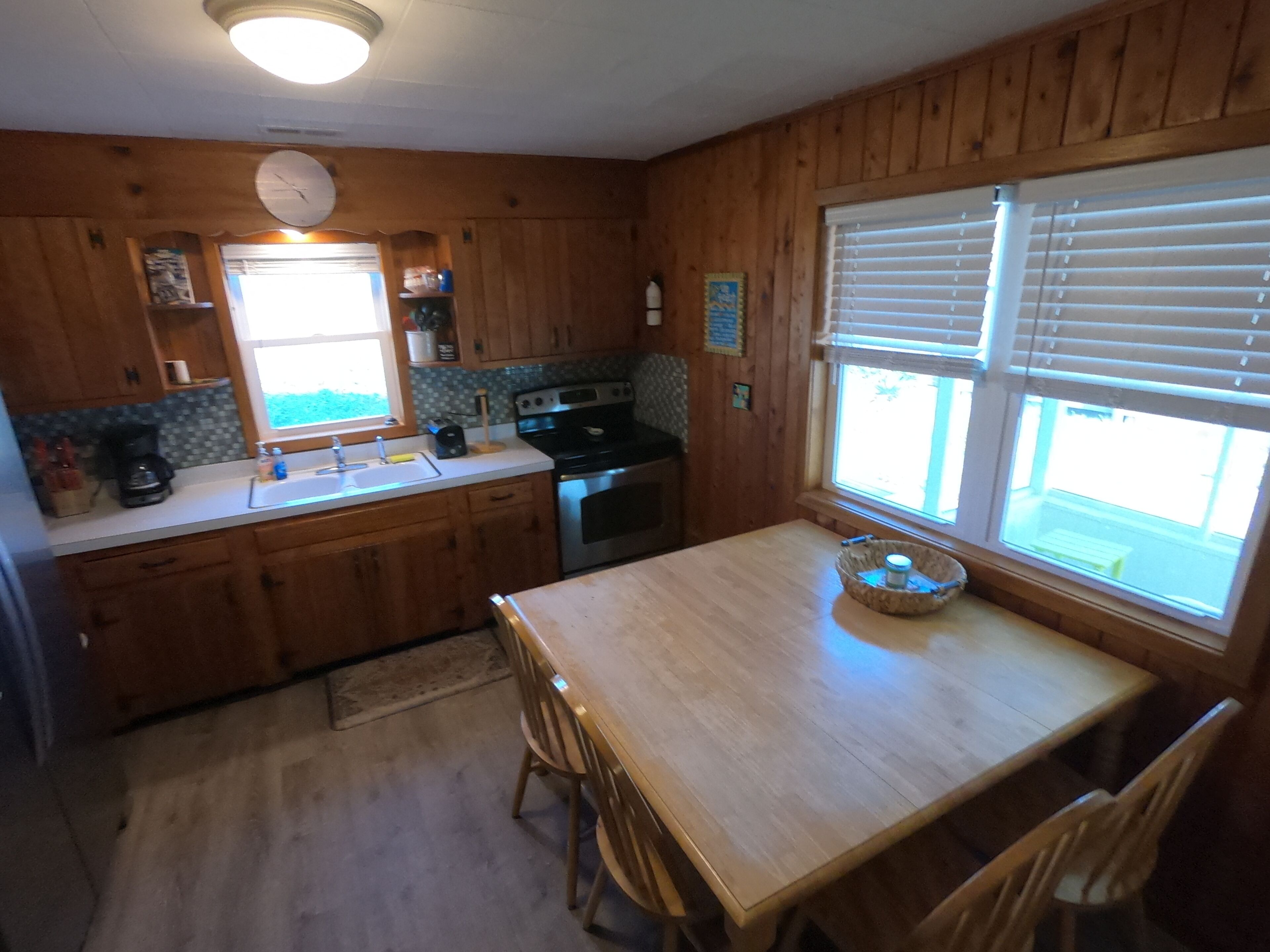 A kitchen with wooden cabinets, a sink, a stove, and a dining table with chairs.