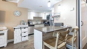 A modern kitchen with white cabinetry, a central island, and wooden chairs.