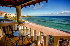 Ein Balkon mit Glastisch und Stühlen mit Blick auf Strand und Meer.