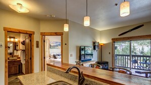 A kitchen with granite countertops, stainless steel sinks, and pendant lighting.