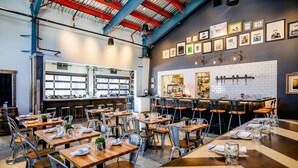 A modern restaurant with a bar area, multiple tables, and chairs.