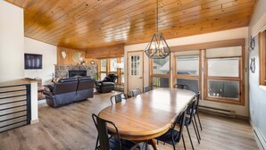 A spacious dining area with a wooden table and chairs, a fireplace, and large windows. - Beautifully decorated home w/fireplace & community hot tub/pool/sauna - Hidden Village Getaway (Gallatin Gateway)