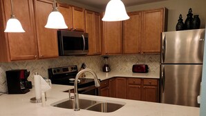 A kitchen with wooden cabinets, stainless steel appliances, a double sink, and pendant lighting. -  Luxury Designer 3/2 Condo! Come Relax & Unwind, and Enjoy!!! (Pigeon Forge)