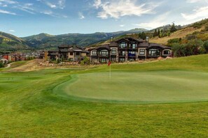 A golf course with a large house in the background.