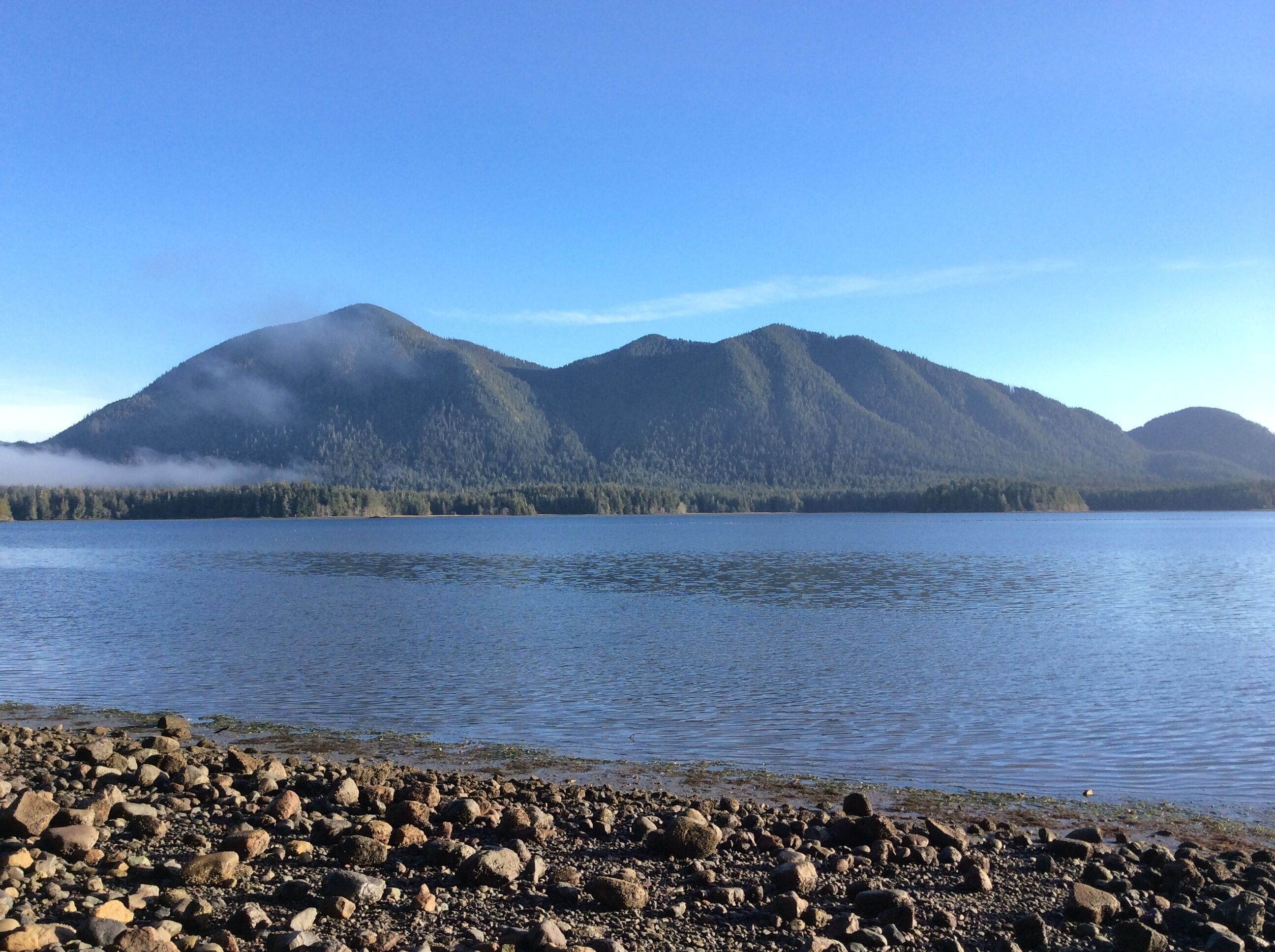Un lac aux rives rocheuses, avec des montagnes en arrière-plan.