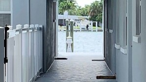 A corridor with a view of a boat dock and palm trees in the distance. - Freshly renovated Treasure Island Condo in 2025! Close to everything! (Treasure Island)