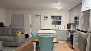A compact kitchen with a dining area, a grey sofa, and a small table with chairs. - Freshly renovated Treasure Island Condo in 2025! Close to everything! (Treasure Island)