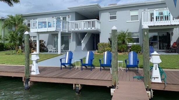 A waterfront property with a dock, blue chairs, and a white fence. - Freshly renovated Treasure Island Condo in 2025! Close to everything! (Treasure Island)