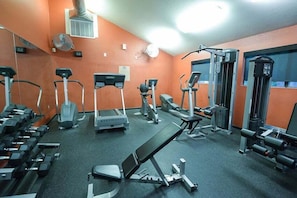 Ein Fitnessstudio mit Laufbändern, Crosstrainern und Gewichtsbänken.