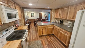 Cocina con gabinetes de madera, encimera de granito, estufa y refrigerador.