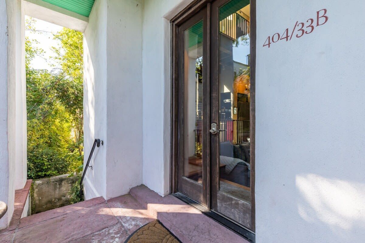 A door with a glass panel, a number '404/33B' on the wall, and a small outdoor area with steps leading to a door.