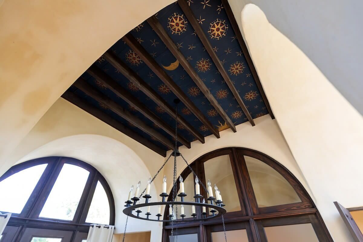 Un lampadari amb nombroses espelmes, un sostre volta amb motius de fulles estrellades, i finestres d'arc.