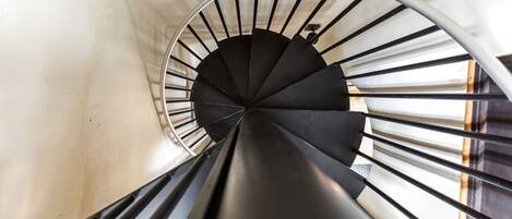 A spiral staircase with a black handrail and white walls.