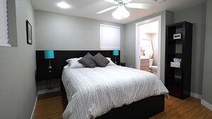 Un dormitorio con cama, mesitas de noche, ventilador de techo y estantería.