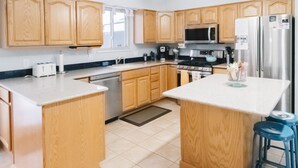 Una cocina con armarios de madera, un refrigerador de acero inoxidable, un microondas y una estufa a gas.