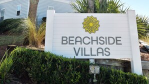 Skilt for Beachside Villas med frit udsyn til en bygning i baggrunden.