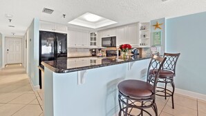 Una cocina moderna con una isla central, armarios blancos y una lámpara en el techo.