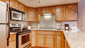 Una cucina con mobili in legno, un forno a microonde, un piano cottura, un lavello e una macchina per il caffè.
