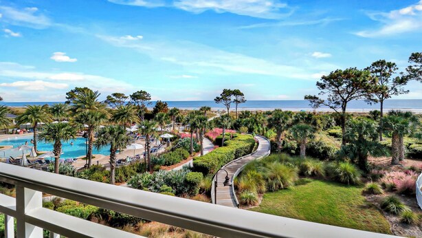 Un complexe hôtelier doté d’une piscine, de palmiers et offrant une vue sur la plage.